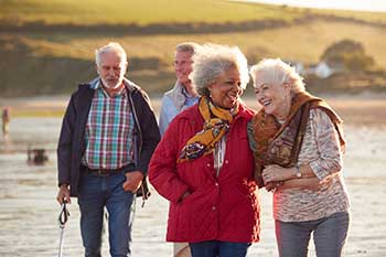 group of older friends walking on a beach